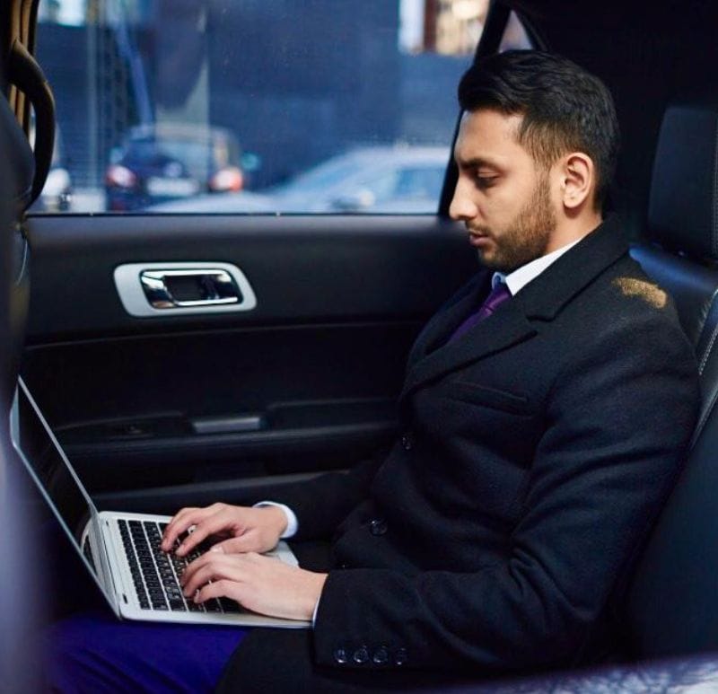 Business professional using laptop in car for smart mobility and transport solutions